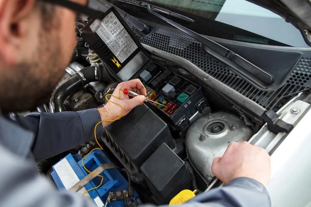 Auto electrician repairing electrical wiring and testing a fuse box in Boonah