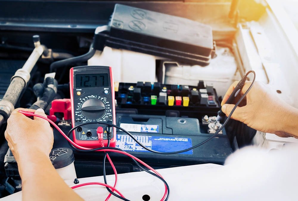 Auto electrician testing a car battery and fuse box with a multimeter in Boonah